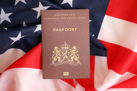 Netherlands passport on big waving flag of United States of America close up. US Visa and...
