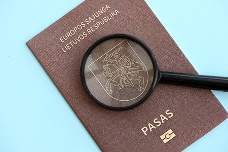 Lithuania passport and magnifying glass on light blue paper background close up. Citizenship details and information conceptの写真素材