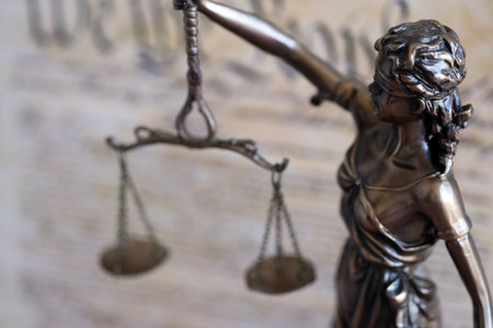 Lady Justice bronze statue on background of US Constitution page close up. Lawsuit and punishment in United States of Americaの写真素材