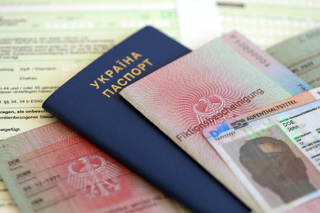German Permanent resident card and document specimen lies with Ukrainian passport on tax form close up. Aufenthaltstitel and Fiktionsbescheinigungの写真素材