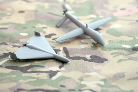 Unnamed grey toy drones models on camouflage fabric close up.の写真素材