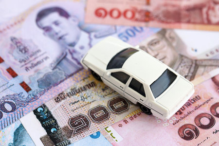 Thai baht currency money bills and toy car close up. The concept of car ownershipの写真素材