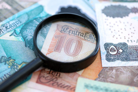 Egyptian pound currency money bills and magnifying glass close up. The concept of financial...