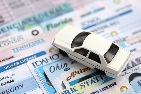 Toy car on big amount of driving licenses from different USA states. Stack of driving license specimen cardsの写真素材