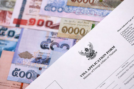 Visa application form to enter Thailand on table with thai money bills close upの写真素材