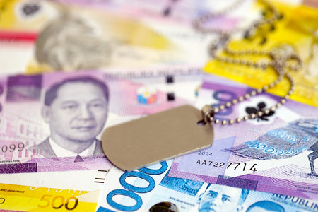 Philippines peso currency money bills and military token close up. The concept of army service
