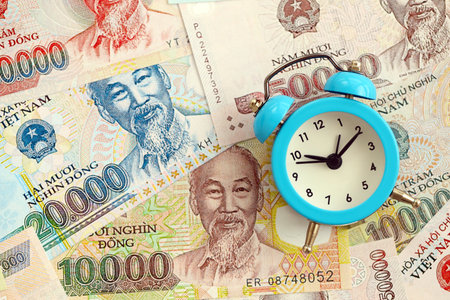 Vietnamese dong currency money bills and alarm clock close up. The concept of time management and incomeの写真素材