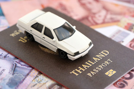 Thai baht currency money bills and car with passport close up. The concept of car ownershipの写真素材