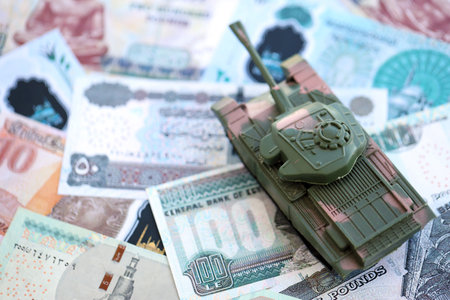 Egyptian pound currency money bills and toy tank close up. The concept of army funds and weapons...
