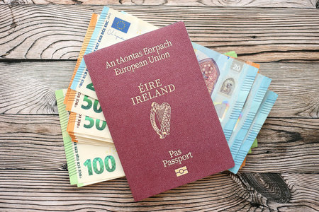 Ireland passport lies with euro money banknotes on wooden background close up. Cash and payments in Europe conceptの写真素材