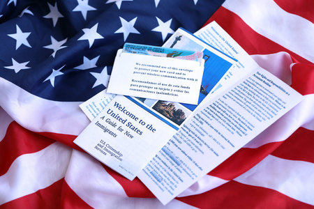Permanent resident green card in envelope and guide for new immigrants lies on US flag close upの写真素材