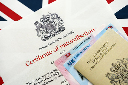 British emergency passport and Certificate of Naturalisation. Yellow color temporary document with residence permit card and driving license close upの写真素材