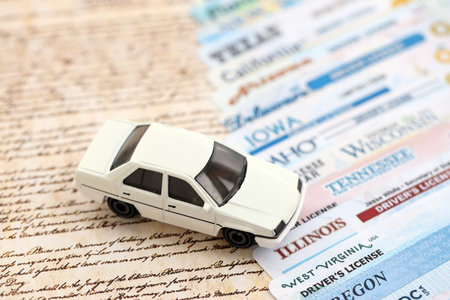 Toy car on big amount of driving licenses from different USA states on constitution page. Stack of driving license specimen cardsの写真素材