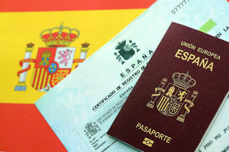 Spanish passport lies on citizenship or naturalization documents on flag of Spain close upの写真素材