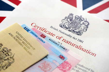 British emergency passport and Certificate of Naturalisation. Yellow color temporary document with residence permit card and driving license close upの写真素材