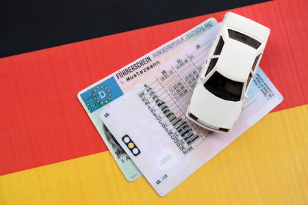 German driving license card called Fuhrerschein with toy car lies on German flag close upの写真素材