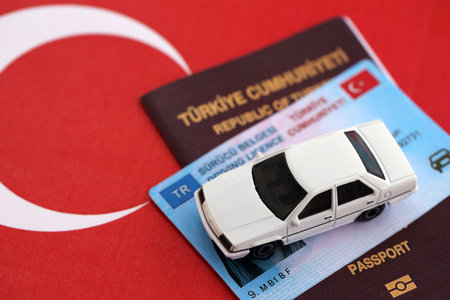 Turkiye driving permit concept. Driver license with passport and toy car on turkish flag close upの写真素材