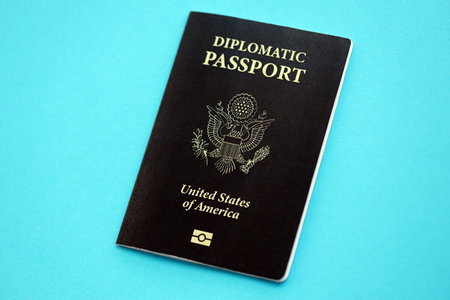 United States diplomatic passport book on light blue paper background close up. Travel document on...
