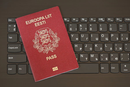 Estonia passport lies on black laptop keyboard buttons background close up. Technologies and control...