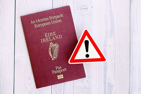 Ireland passport with exclamation sign on white wooden background close up. Problems with citizenship in Europe conceptの写真素材
