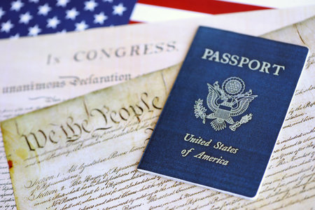 US passport on replica pages of the United States Constitution close up with US flag background