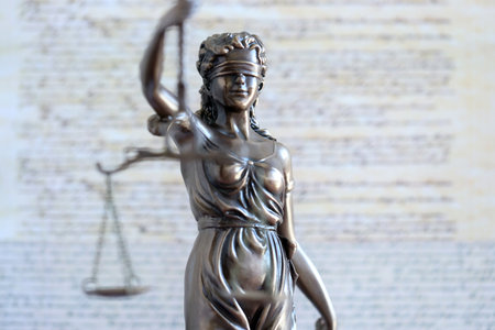 Lady Justice bronze statue and US Constitution blurred page close up. Lawsuit and justice in United...
