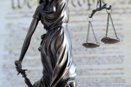 Lady Justice old statue and US Constitution blurred page close up. Lawsuit and justice in United...