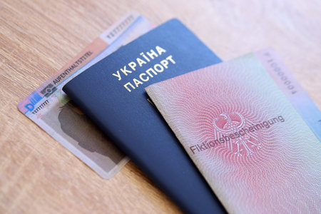 German Permanent resident card and document specimen lies with Ukrainian passport on wooden table close up. Aufenthaltstitel and Fiktionsbescheinigungの写真素材