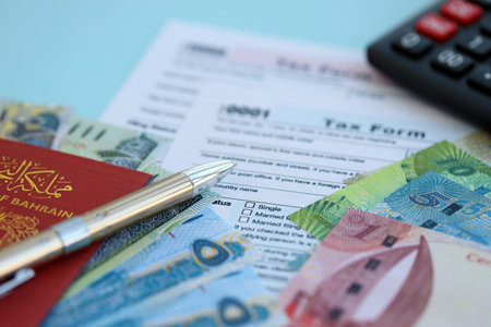 Bahraini dinar money bills and calculator with tax form close up on blue. Taxation and accounting conceptの写真素材