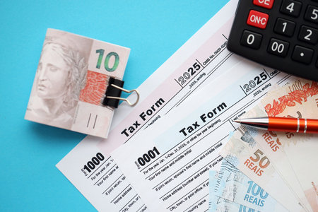 Brazilian reais banknotes with calculator and tax form. The current Brazil real money bills and tax...