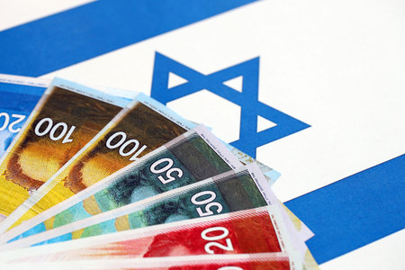 Israel New Shekels banknotes on national flag. The current Israel money bills lies on flag in big amount. The concept of business and investment in Israelの写真素材