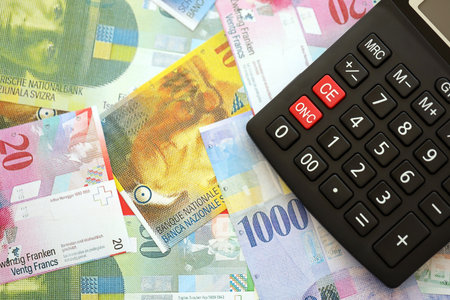 Swiss franc banknotes and calculator. The current francs money bills and calc lies on table in big amount. The concept of taxation and money count in Switzerlandの写真素材