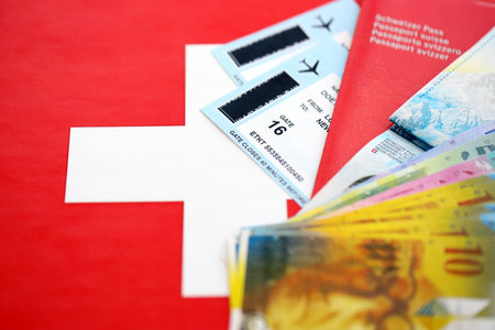Swiss franc banknotes and passport with tickets on flag. The current francs money bills and biometrical pass lies on flag. The concept of travel and vacation in Switzerlandの写真素材