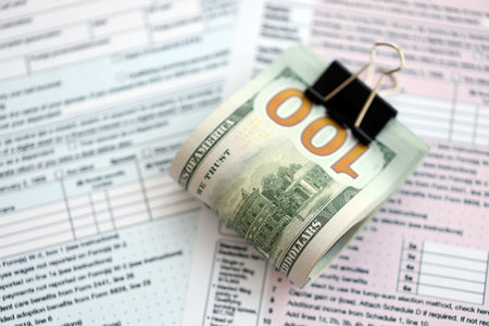 Big amount of United States dollar bills on table with 1040 individual income tax return form....