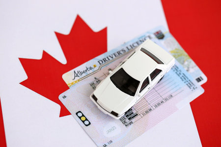 Canadian driving permit concept. Toy car and driver license on flag close upの写真素材