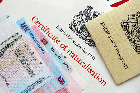 British emergency passport and Certificate of Naturalisation. Yellow color temporary document with residence permit card and driving license close upの写真素材