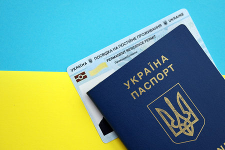 Ukrainian residence permit card or permanent resident card with passport on Ukraine flag close upの写真素材