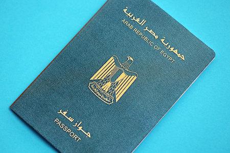 Egyptian passport book on light blue paper background close up. Travel document on blue surface