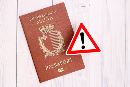 Malta passport with exclamation sign on white wooden background close up. Problems with citizenship...
