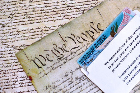 Permanent resident green card in envelope lies on US constitution page close up