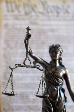 Lady Justice bronze statue with scales on background of US Constitution page close up. Lawsuit and punishment in United Statesの写真素材
