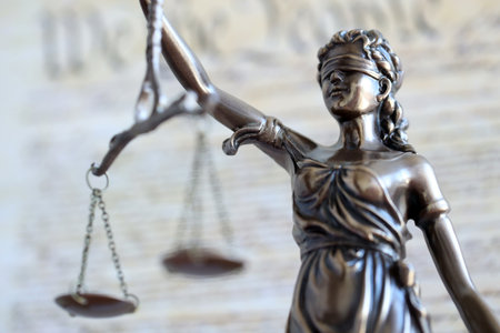 Lady Justice bronze statue with scales on background of US Constitution page close up. Lawsuit and punishment in United Statesの写真素材