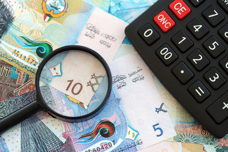 Kuwaiti dinar currency money bills and calculator with magnifying glass close up. The concept of...