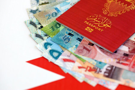 Bahraini dinar currency money bills and passport lies on flag close up. The concept of travel and...