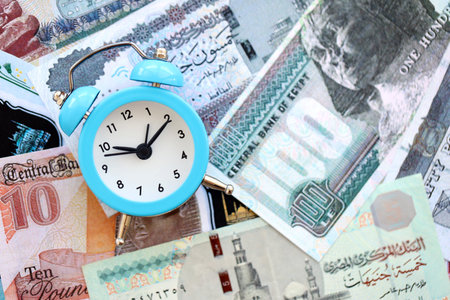 Egyptian pound currency money bills and alarm clock close up. The concept of time management and...