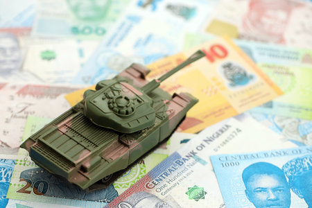 Nigerian naira currency money bills and toy tank close up. The concept of army funds and weapons...
