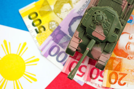 Philippines peso currency money bills and toy tank on flag close up.の写真素材