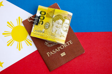 Philippines peso currency money bills and passport lies on flag close up. The concept of travel and vacationの写真素材