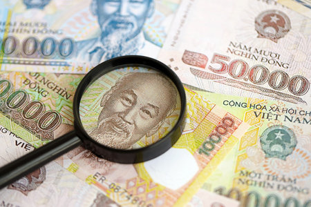 Vietnamese dong currency money bills and magnifying glass close up. The concept of financial monitoring and taxationの写真素材