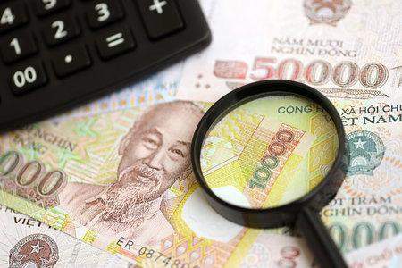 Vietnamese dong currency money bills and calculator with magnifying glass close up. The concept of taxation and money countの写真素材